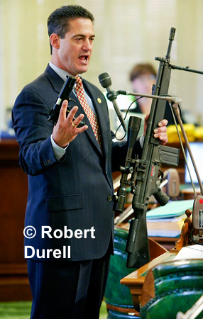 FIRED UP  ---  Sometimes photos tell a false story - or do they? I wasn't the only one who was a little nervous as Assemblyman Todd Spitzer brought very realistic toy guns to the Assembly floor that day. Everyone had been warned, and knew they were toys, but Spitzer's props still silenced the usually loquacious legislators.  He was seeking votes for a bill to ban the public display of such weapons. The fear was real and the scare tactic had its desired affect. His bill passed easily. 
August 15, 2004

