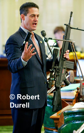 FIRED UP --- Sometimes photos tell a false story - or do they? I wasn't the only one who was a little nervous as Assemblyman Todd Spitzer brought very realistic toy guns to the Assembly floor that day. Everyone had been warned, and knew they were toys, but Spitzer's props still silenced the usually loquacious legislators. He was seeking votes for a bill to ban the public display of such weapons. The fear was real and the scare tactic had its desired affect. His bill passed easily.
August 15, 2004