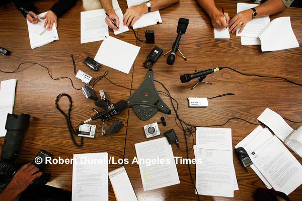 THE PRESSER --- For a photographer on a deadline to produce a good image, a call-in press conference is akin to water torture. What's there to shoot? For this event, the press release failed to mention it was a conference call, so I had showed up. I made the best of it, standing on a chair to capture the importance - and disembodied nature - of the event via the crazy quilt of notebooks and microphones. June 20, 2003
