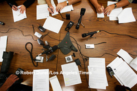 THE PRESSER --- For a photographer on a deadline to produce a good image, a call-in press conference is akin to water torture. What's there to shoot? For this event, the press release failed to mention it was a conference call, so I had showed up. I made the best of it, standing on a chair to capture the importance - and disembodied nature - of the event via the crazy quilt of notebooks and microphones. June 20, 2003

